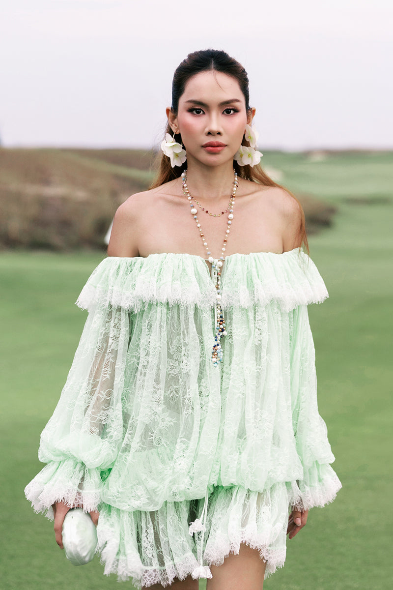 Valenciani off-shoulder lace mini dress displayed on hanger, featuring intricate lace details and a fitted silhouette.