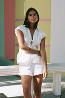 White DEIA Shorts by Summer Away displayed on a hanger, showcasing casual summer shorts with a relaxed fit.