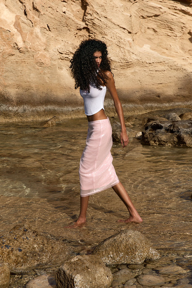 Pink midi skirt from IKINITA's Sunrise Skirt collection, featuring flowing fabric and stylish design.