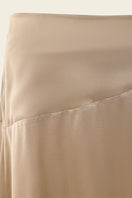 Nude IKINITA Nausica midi skirt displayed on a model, showcasing its elegant flowy fabric and stylish design.