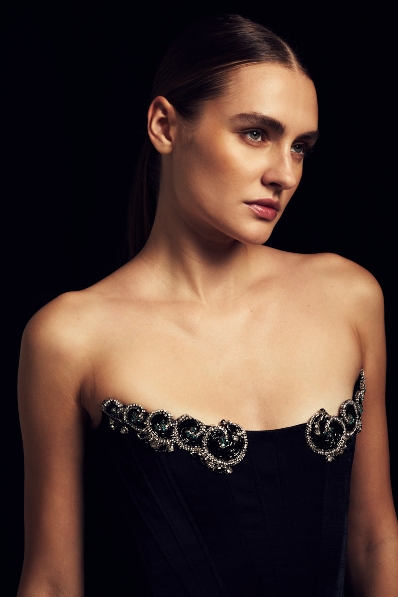 Black IKINITA Wave Skirt, a stylish mini skirt with wave design, shown in a close-up image highlighting the fabric and pattern.