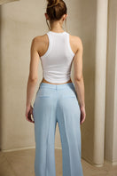 White and blue water-themed top by IKINITA, featuring a stylish design, displayed on a mannequin against a neutral background.
