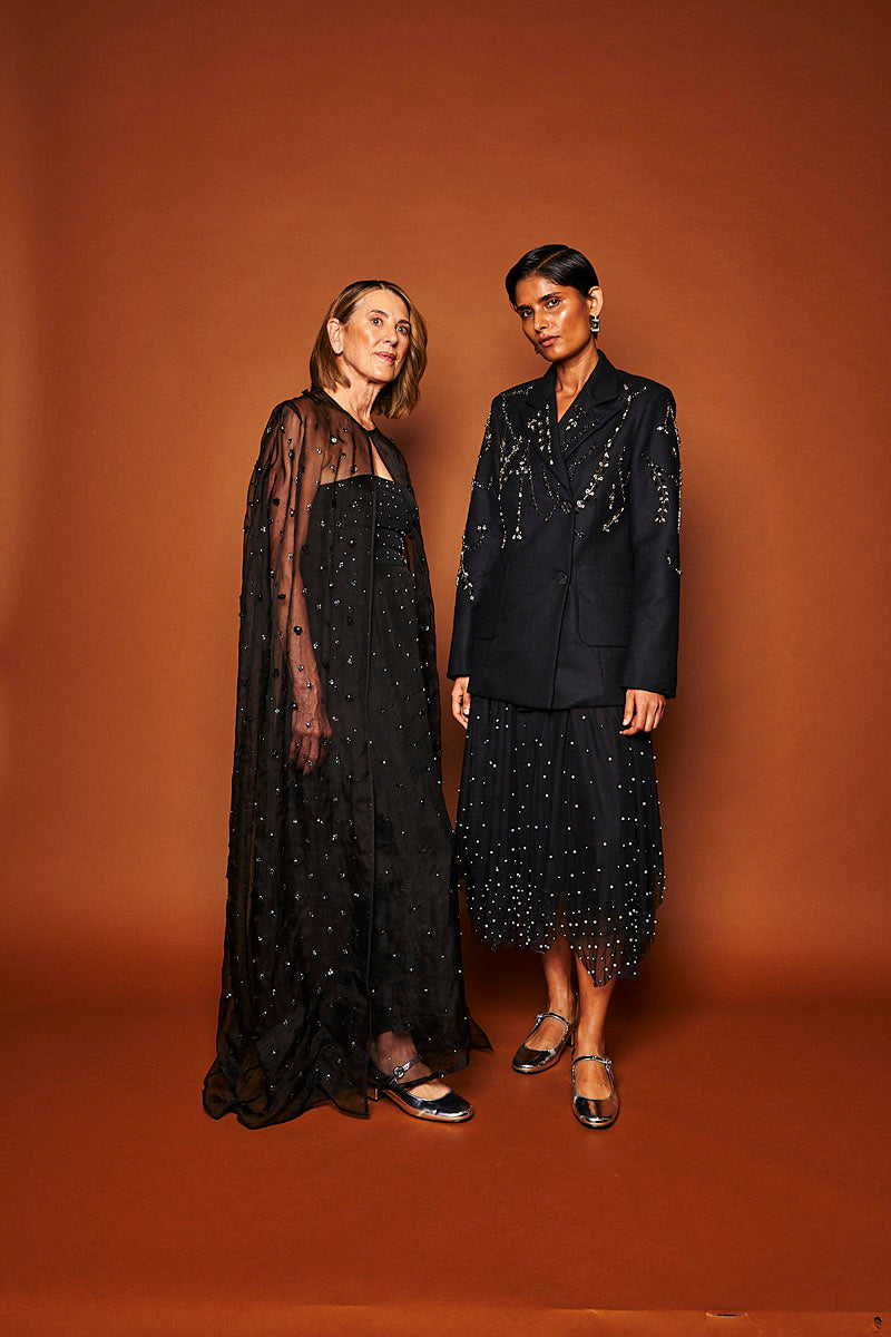 Beaded floral maxi cape in noir by Mastani, featuring intricate beadwork and elegant design, worn as a stylish coat.