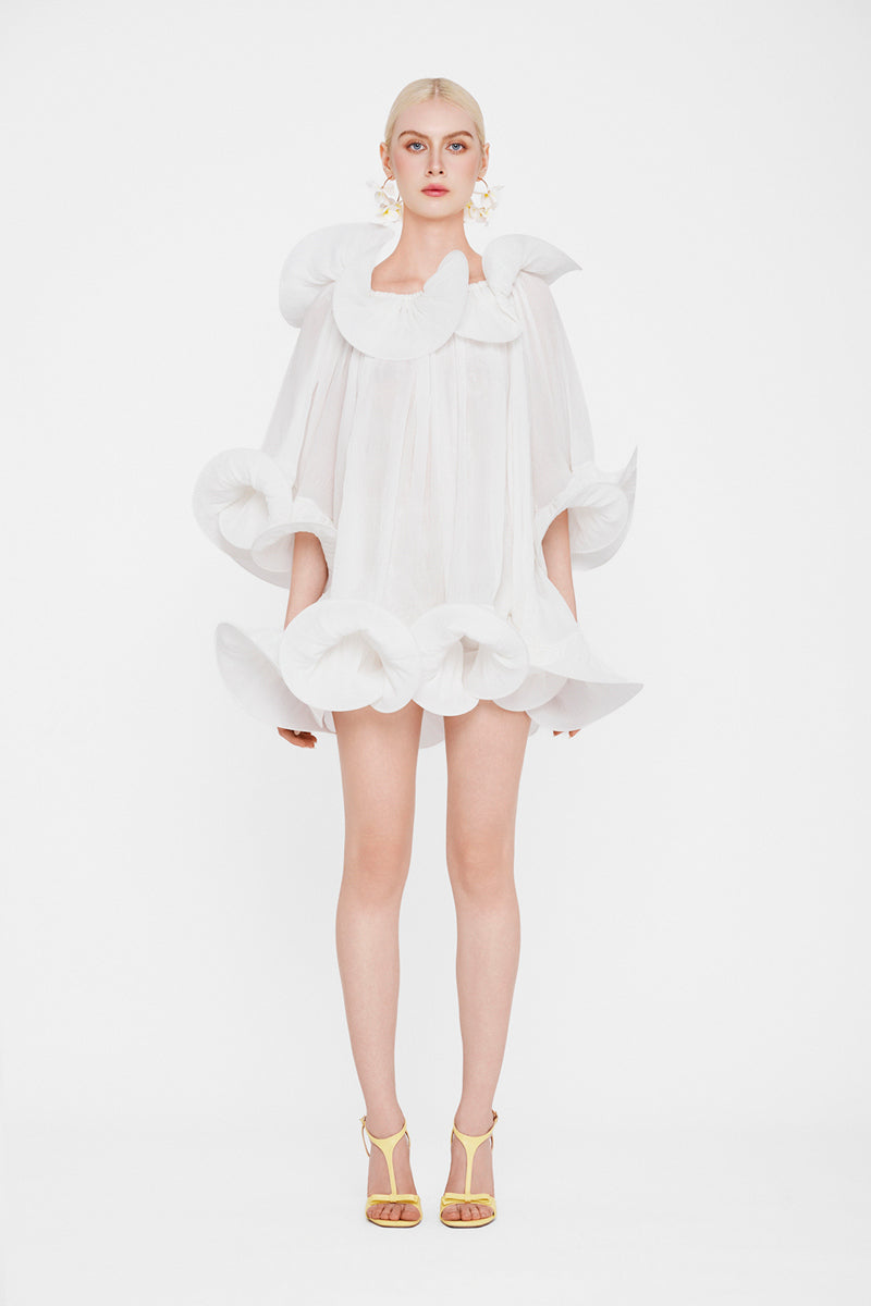 White Valenciani Origami Cloud mini dress, lightweight fabric with modern fold details, displayed on a hanger.