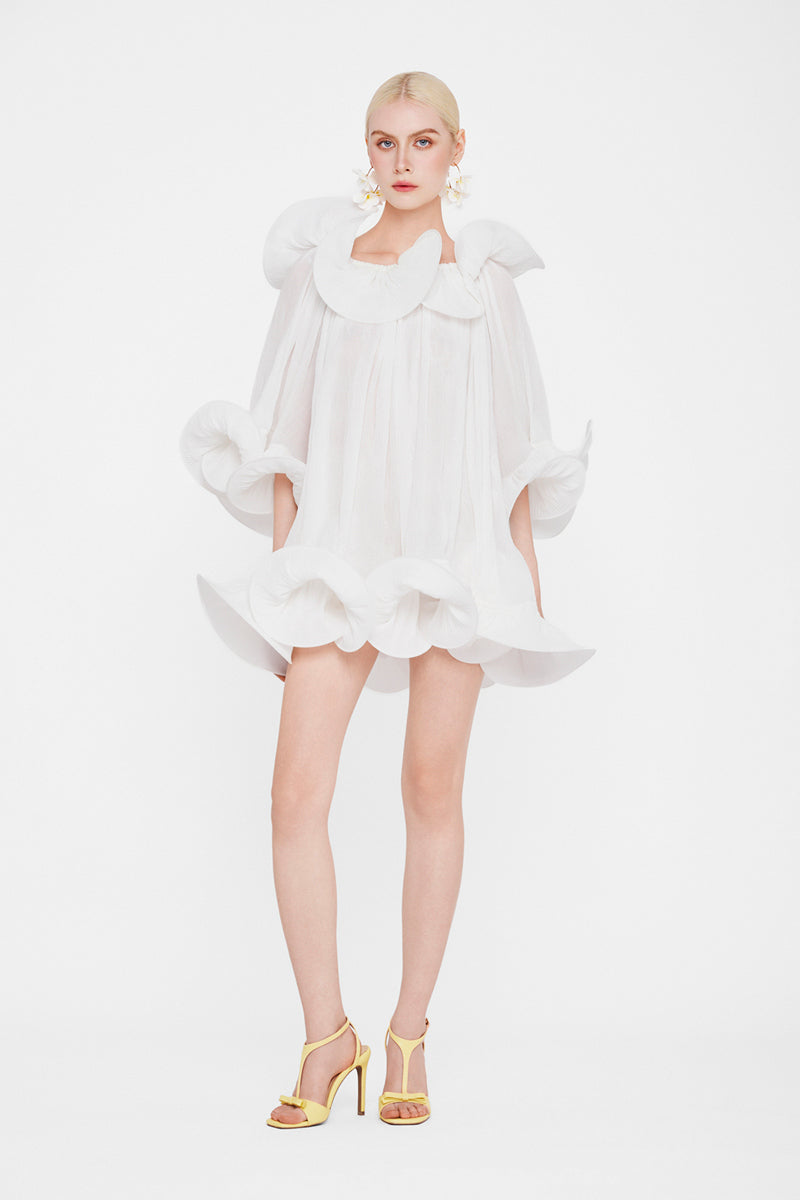 White Valenciani Origami Cloud mini dress displayed on a hanger with detailed fabric texture and simple background.