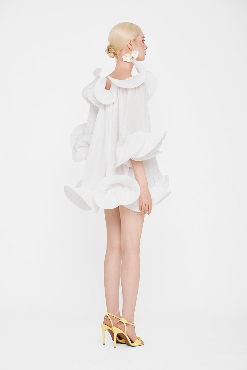 White Valenciani Origami Cloud mini dress displayed on a hanger, showcasing its elegant, lightweight fabric and modern design.