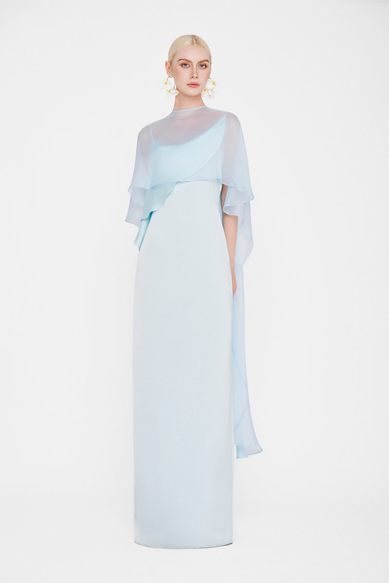Ice blue maxi dress called The Galatea Cape Gown by Valenciani, featuring flowing fabric and elegant cape details.