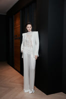 White LEKIEU CAEN pants displayed on a hanger with a tailored fit and clean design.