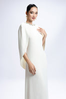 Elegant white Valenciani gown with a cowl back and cape sleeve, featuring flowing fabric and sophisticated design.