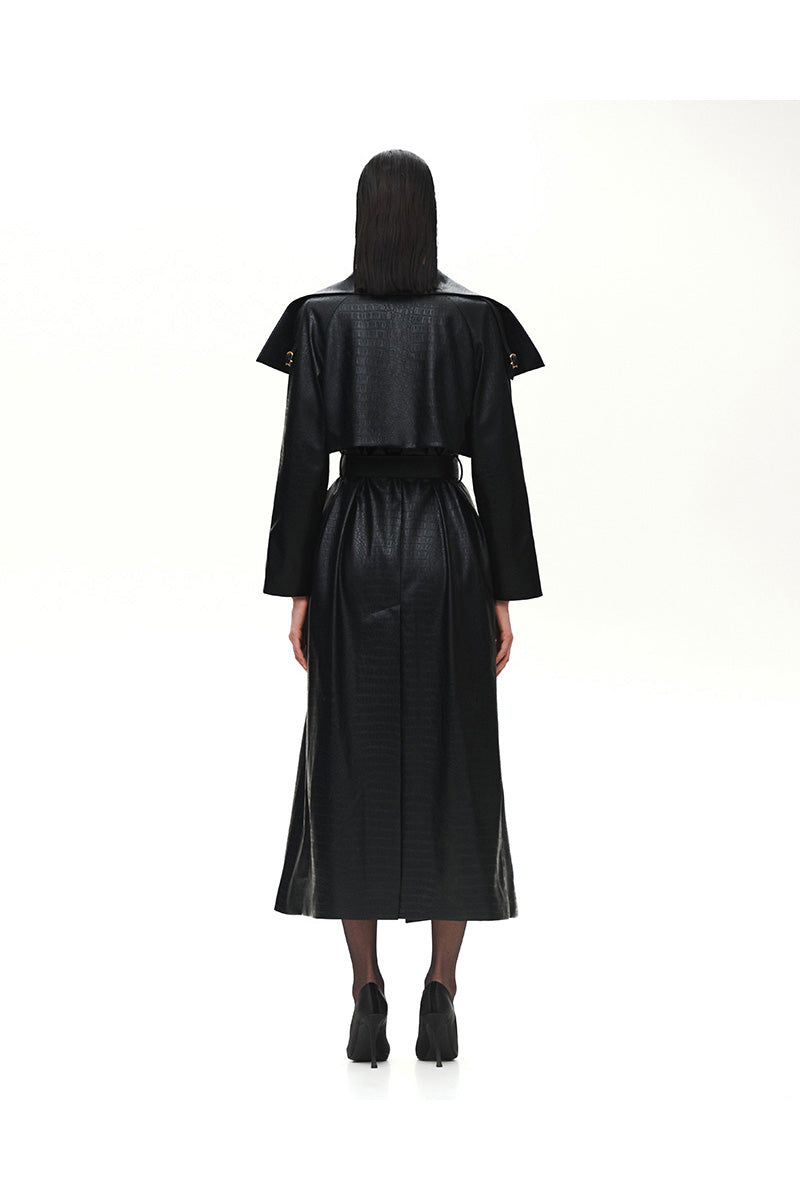 Black crocodile-embossed leather trench coat by Kris Marán, showcasing the textured crocodile pattern and stylish buckle detail.