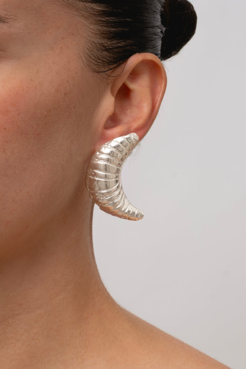 Silver croissant-shaped earrings by Oz Objects featuring detailed, textured design perfect for stylish accessories.