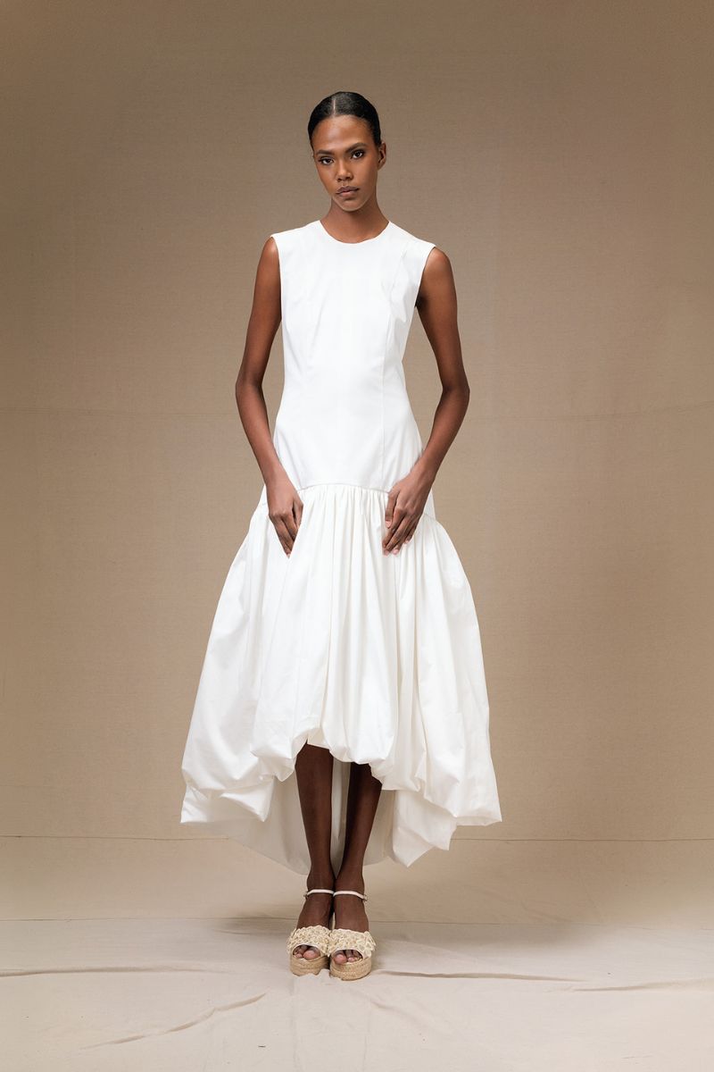 Ivory Cupula Dress by ANA + MARIA, a flowing maxi dress with elegant design, displayed on a hanger against a neutral background.