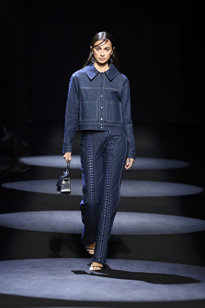 Blue denim jeans with chain accents on the legs, by JC Pajares, featuring a modern, edgy style perfect for casual wear.