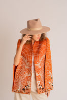 Nadya Shah Clementine Cape jacket in soft fabric, draped over a hanger, showcasing elegant design and neutral color.