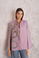 Nadya Shah Hydra Lilac Cape jacket displayed outdoors, featuring flowing fabric and elegant design in soft lilac color.