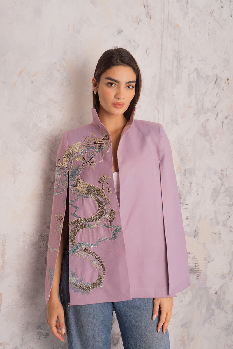 Nadya Shah Hydra Lilac Cape jacket displayed outdoors, featuring flowing fabric and elegant design in soft lilac color.