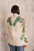 Nadya Shah Cara Leaf Cape jacket displayed on a hanger, featuring a leaf pattern and lightweight fabric for stylish layering.