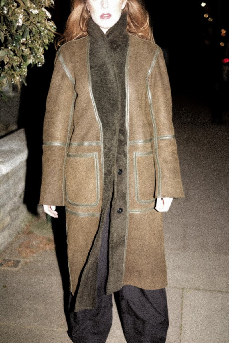 Verheyen ZINA biker green shearling coat on a hanger, showcasing its textured shearling material and stylish design.
