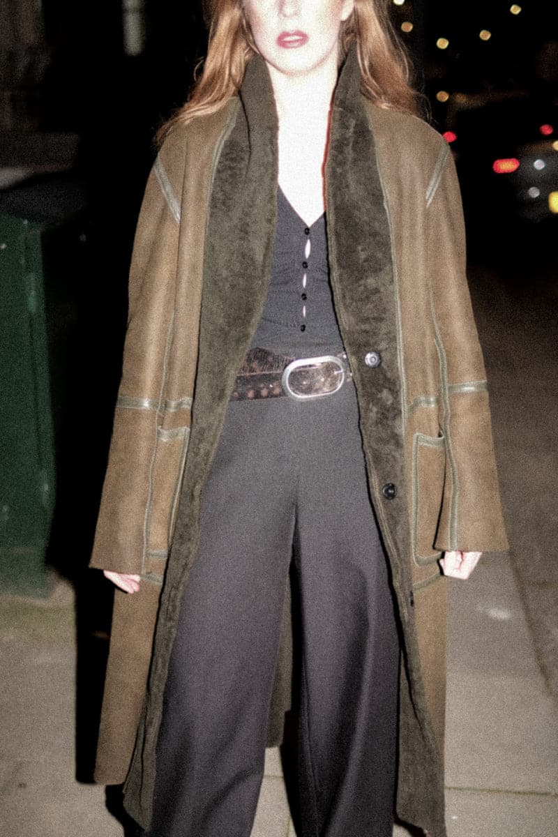 Verheyen ZINA biker green shearling coat displayed on a hanger, showcasing its stylish collar and textured shearling material.