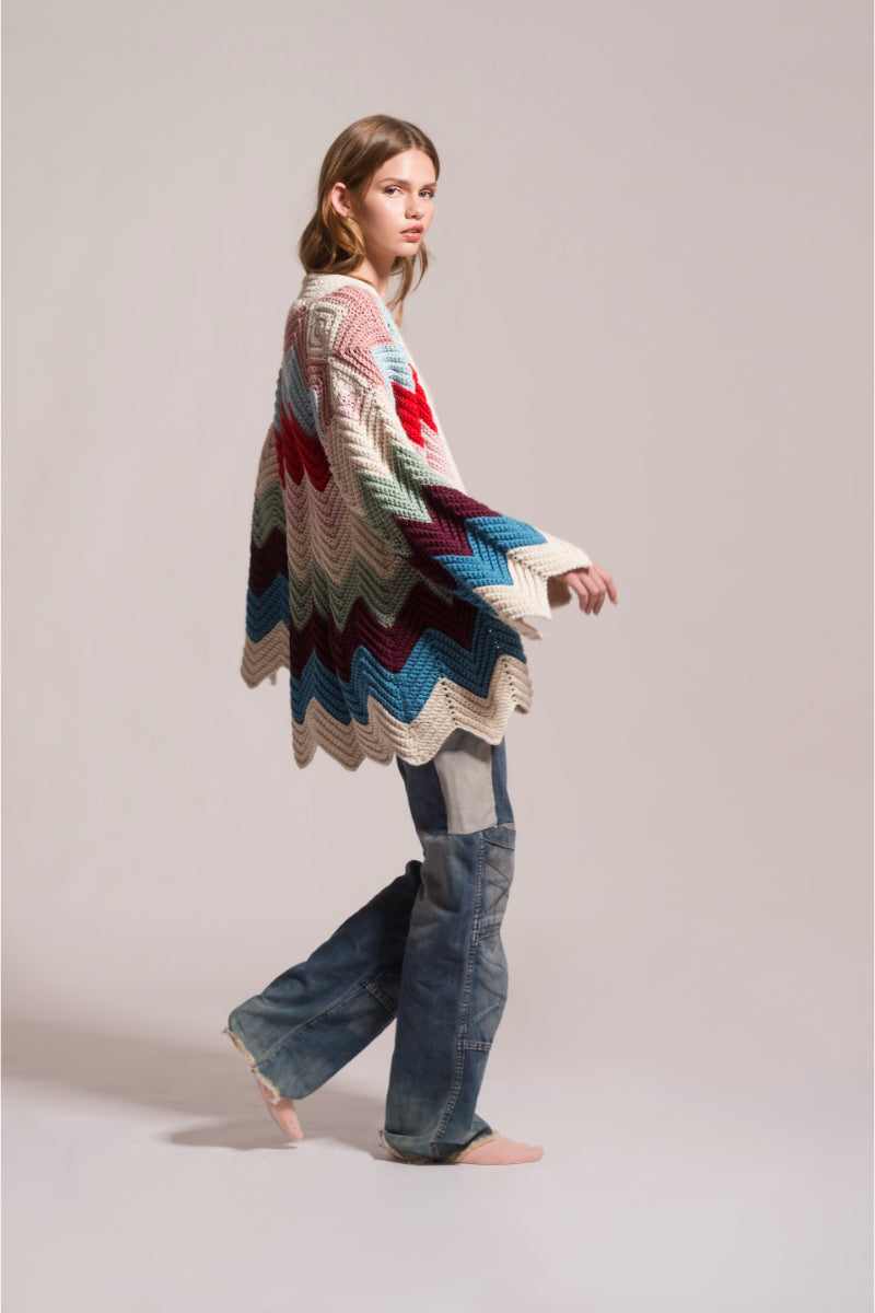 First Born Knits Ziggy knitted cardigan displayed on a hanger with a cozy, textured knit pattern.