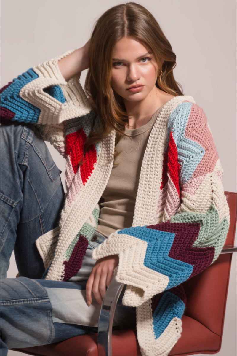 First Born Knits Ziggy knitted cardigan, cozy knitwear with a textured pattern, shown on a hanger against a neutral background.