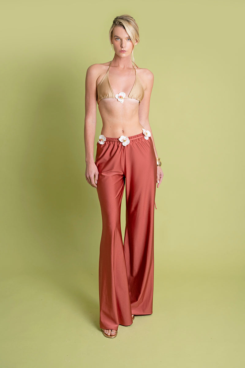 Laura Escobar Flora Pants in coral, stylish women's pants with a vibrant coral color, shown on a model in a casual setting.