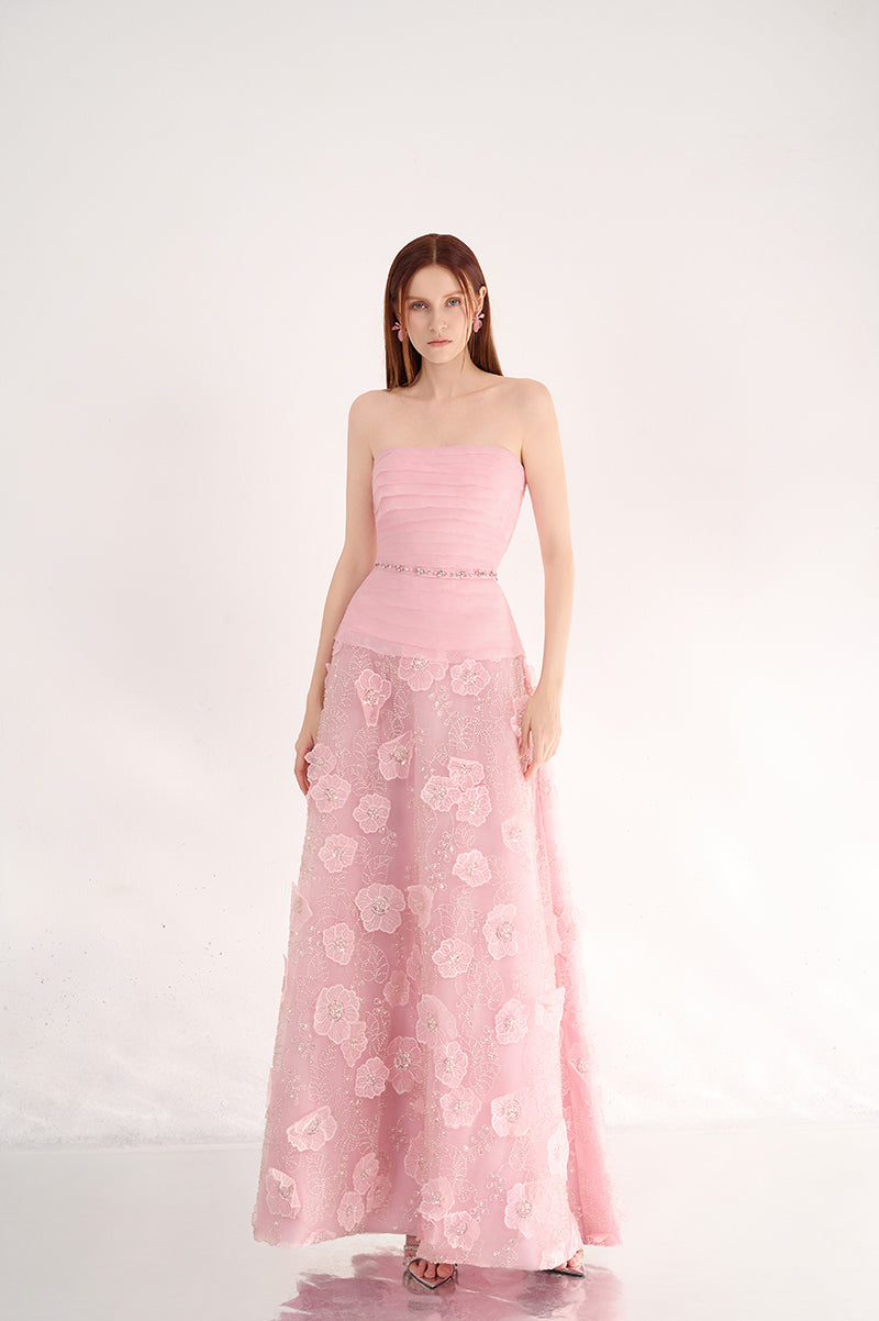 Elegant pink strapless gown with floral details by Happy Clothing, shown on a model with flowing fabric and intricate floral accents.
