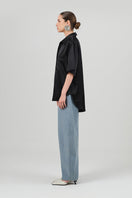 Black satin Rosa shirt by Izakova, featuring a sleek fit and elegant design, displayed on a hanger against a neutral background.