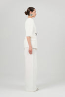 Izakova Tessa white pants with a tailored fit, shown hanging on a rack with a smooth fabric texture and clean design.