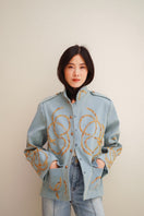 Nadya Shah Daley Denim Cargo jacket with multiple pockets, classic blue denim fabric, and button closure, displayed on a hanger.