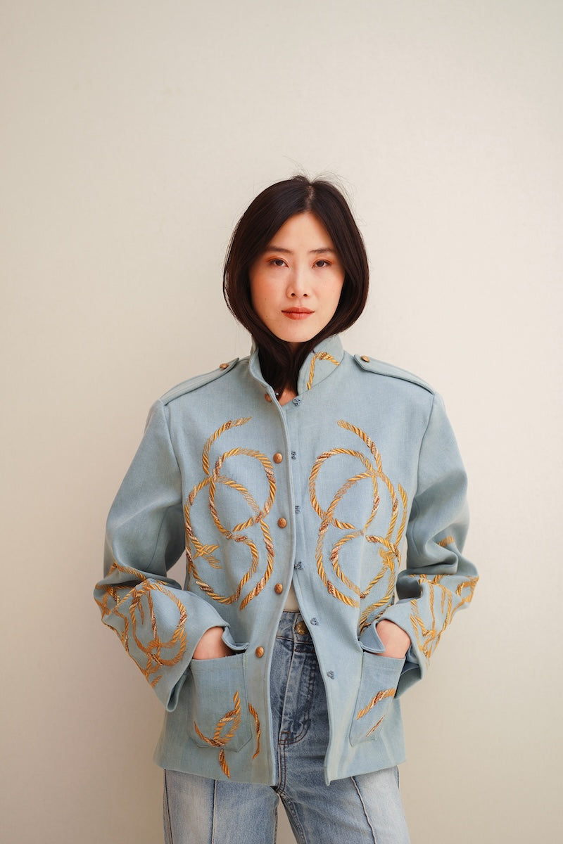 Nadya Shah Daley Denim Cargo jacket with multiple pockets, classic blue denim fabric, and button closure, displayed on a hanger.