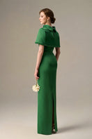 Dark green taffeta gown by I.H.F with a cropped cape and inverted lapel, featuring elegant details and a fitted silhouette.