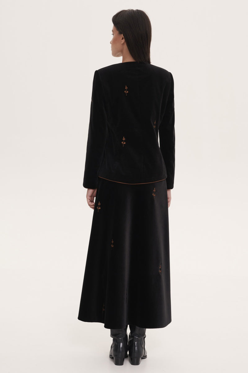 Black rose embroidered midi skirt from DELEGAN, showcasing intricate floral embroidery and a flowing, elegant design.
