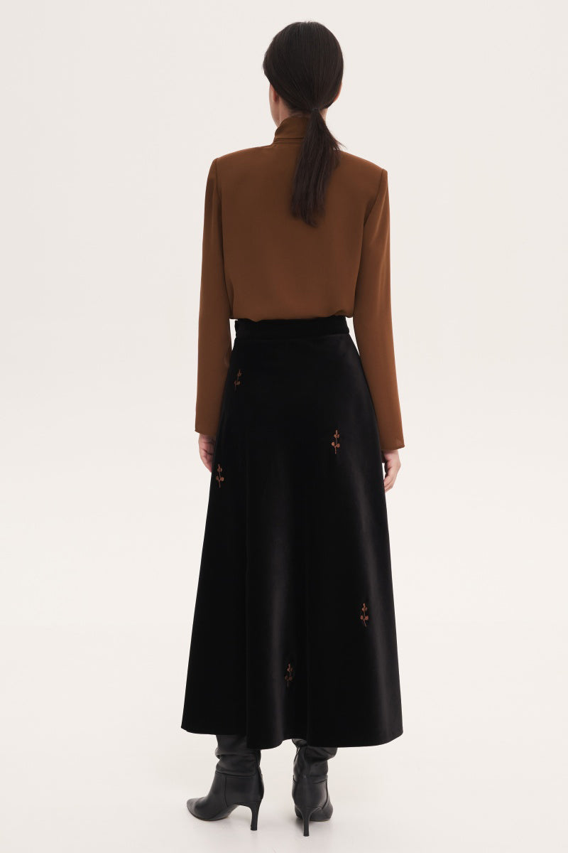 Black rose embroidered midi skirt by Delegan, showcasing detailed floral embroidery and elegant flowy fabric.