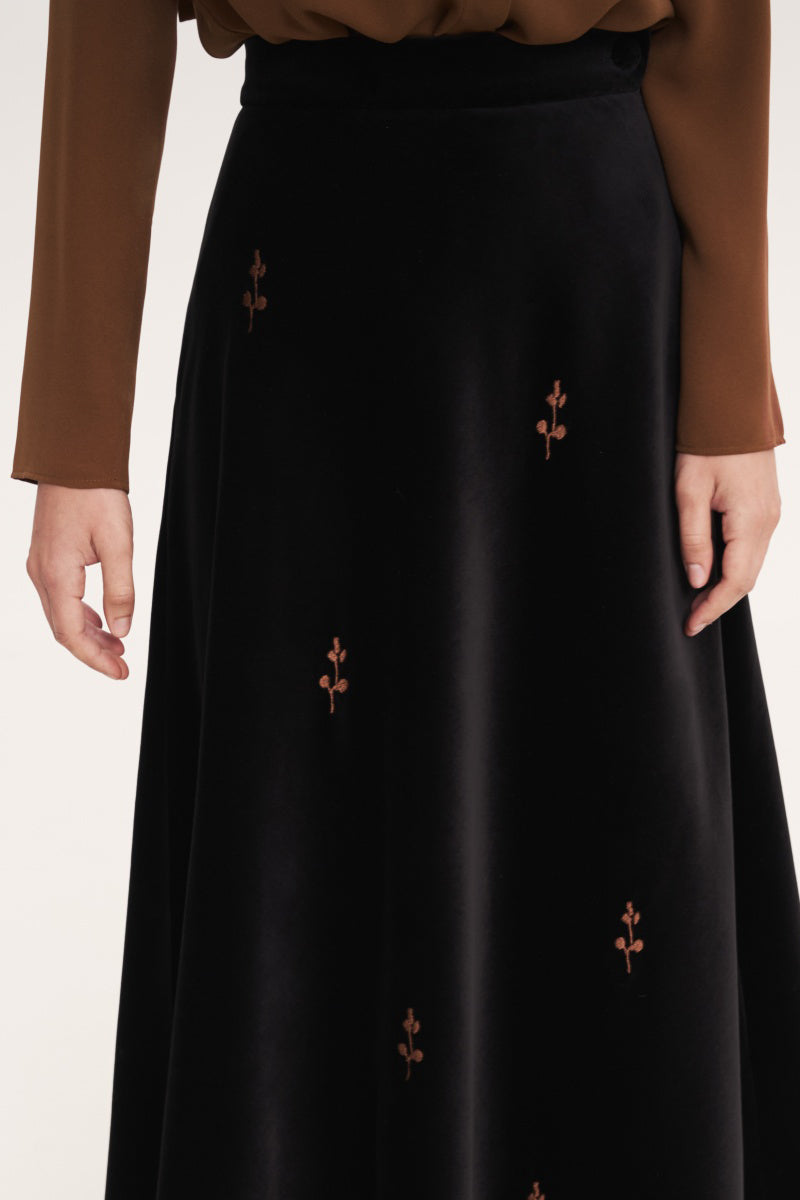 Black rose embroidered midi skirt by Delegan, showcasing intricate floral embroidery and a flowing midi length.