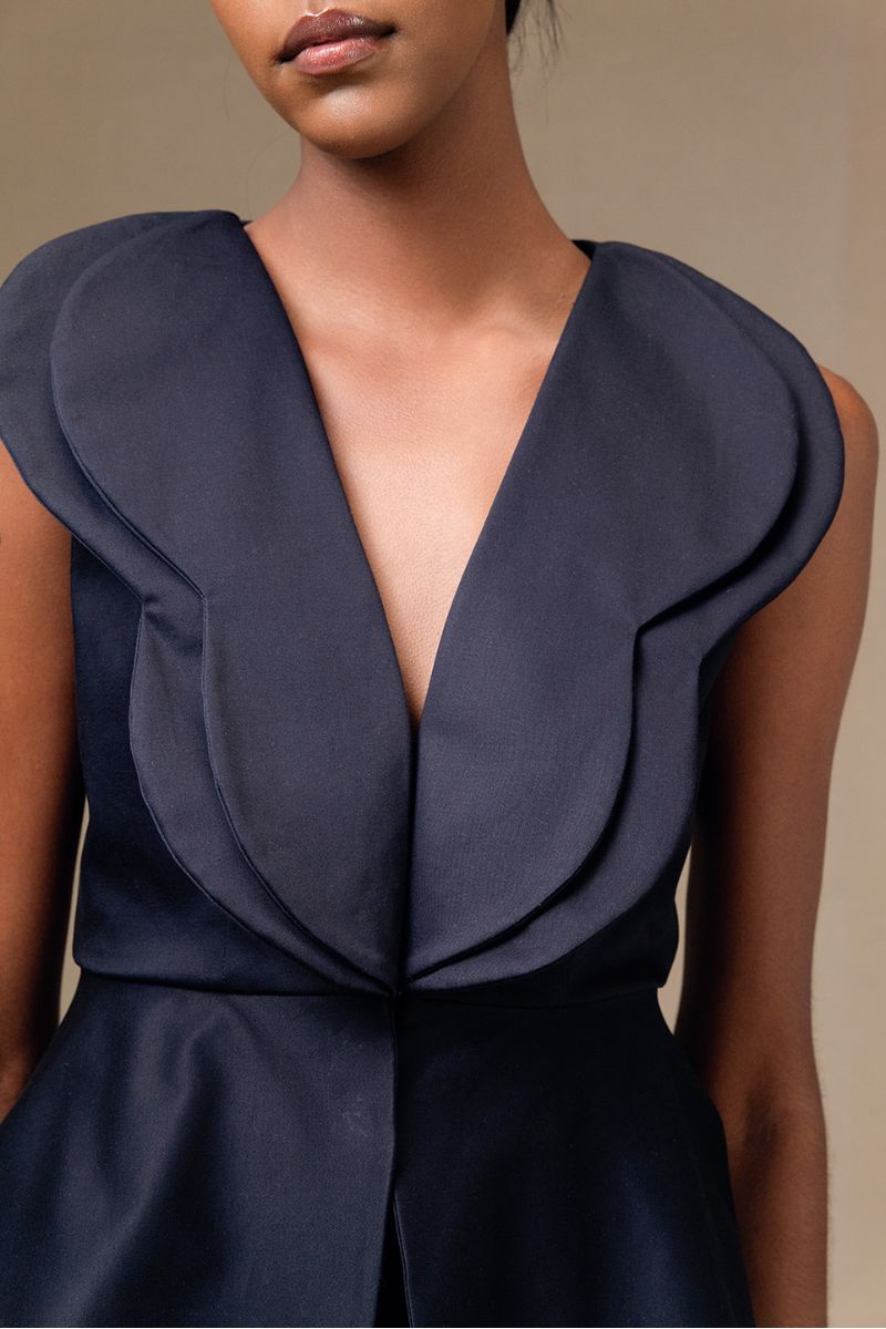 Navy blue Della top by ANA + MARIA, shown in a campaign photo, with a close-up of the stylish sleeveless design and soft fabric.