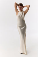 Cream silk satin halter-neck maxi dress by Serenity, flowing design with elegant drape and stylish silhouette.