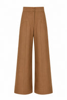 Tan ANA + MARIA PINO pants displayed on a hanger, showcasing their stylish design and fabric texture.