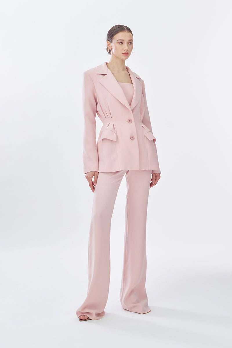 Pink doll-shaped suit jacket from Stolen Stores with long pants, styled in a classic, casual fashion.