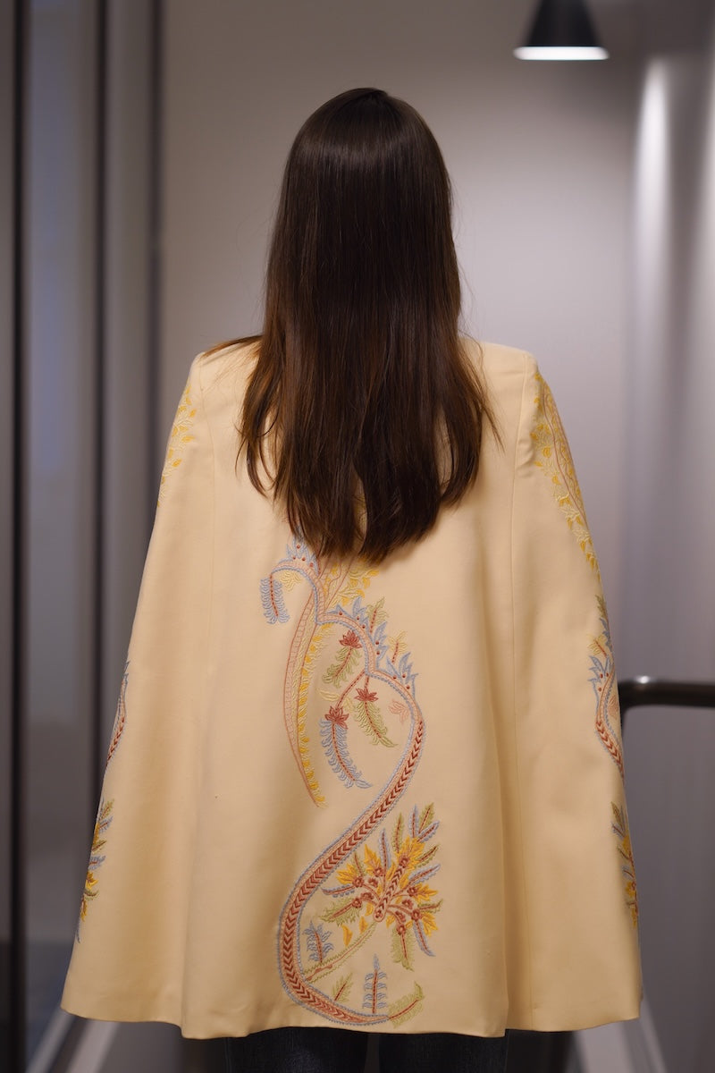 Nadya Shah Dorian Ivory Cape jacket shown from the back, featuring elegant flowing fabric and stylish design.