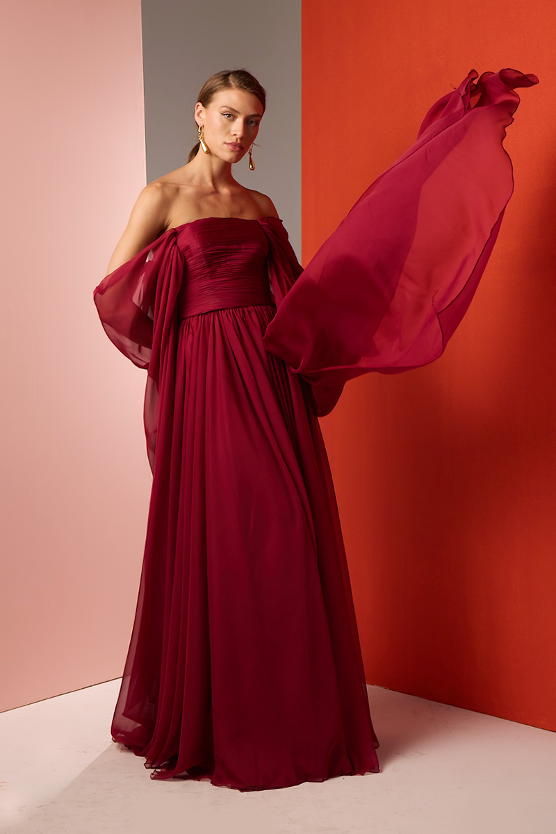 Red strapless gown by Joanna Andraos featuring elegant draping and a fitted bodice, suitable for formal occasions.