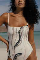 Nelblu Tierra One Piece Swimsuit featuring a stylish design, showcased on a model in a vibrant outdoor setting