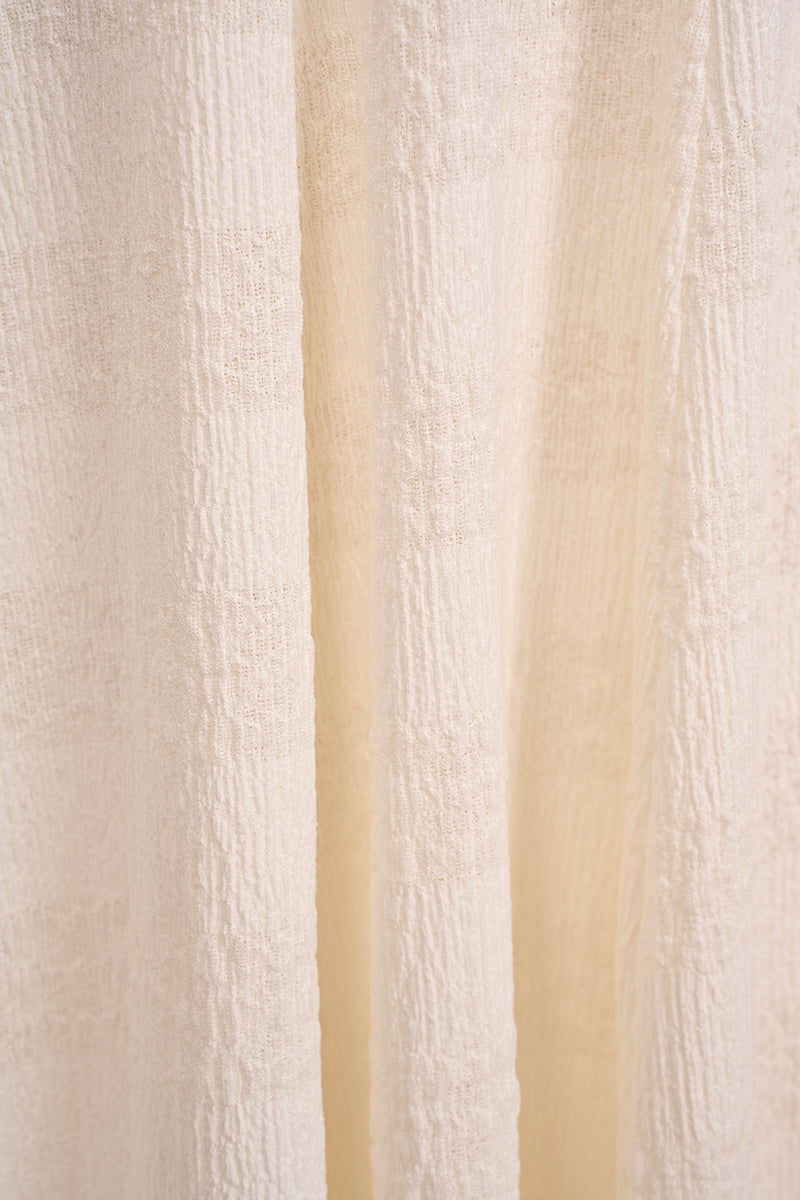 White ELOWEN maxi dress by EEGEN STUDIO displayed on a hanger, showcasing its flowing fabric and elegant design.
