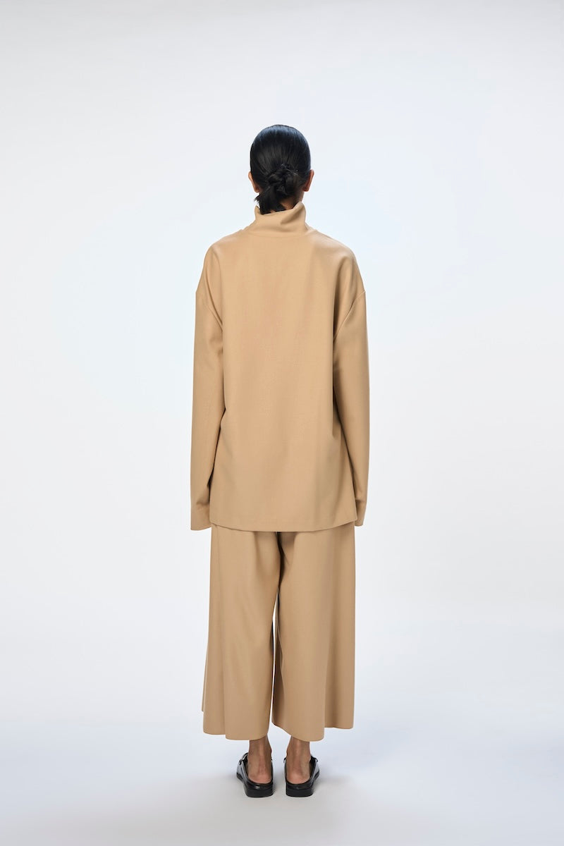Cream-colored URA EIRA TOP made of soft fabric, featuring a relaxed fit and stylish neckline, perfect for casual wear.