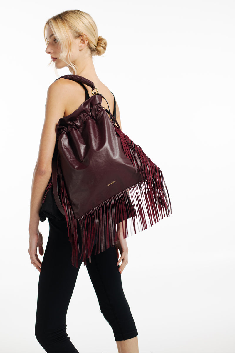ISIDORA MALVA Elena pouch top handle bag with burgundy fringes and textured design, stylish accessory for everyday use.
