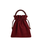 ISIDORA MALVA Elena suede top handle pouch in burgundy, featuring a sleek design and soft suede texture.