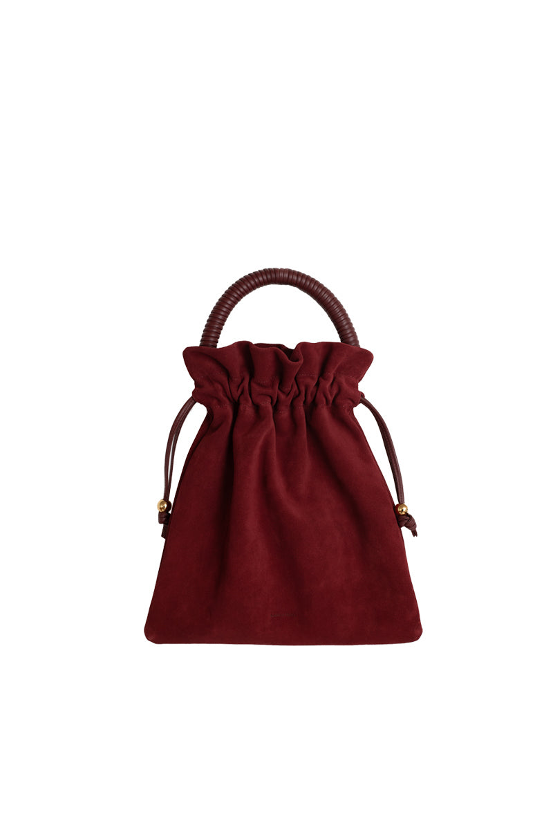 ISIDORA MALVA Elena suede top handle pouch in burgundy, featuring a sleek design and soft suede texture.