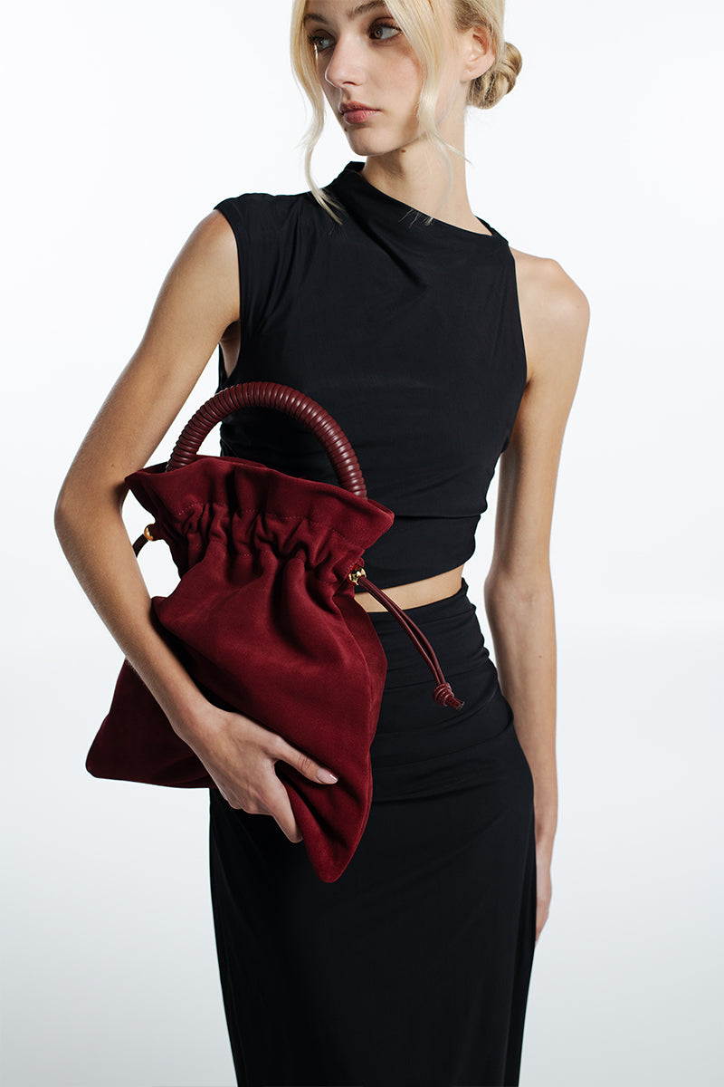 ISIDORA MALVA Elena suede pouch in burgundy, top handle bag with sleek design and soft suede texture.
