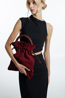 ISIDORA MALVA Elena suede pouch in burgundy, top handle bag with sleek design and soft suede texture.