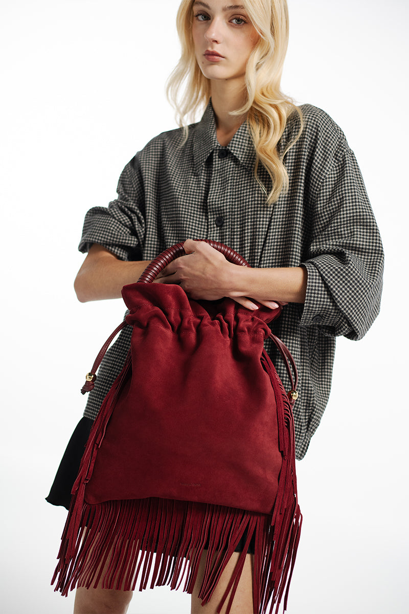 ISIDORA MALVA Elena suede top handle bag with burgundy fringes, showcasing its textured suede material and stylish design.
